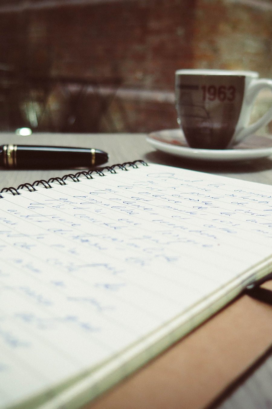 Notizblock mit Handschrift, Füllfeder und Kaffeetasse